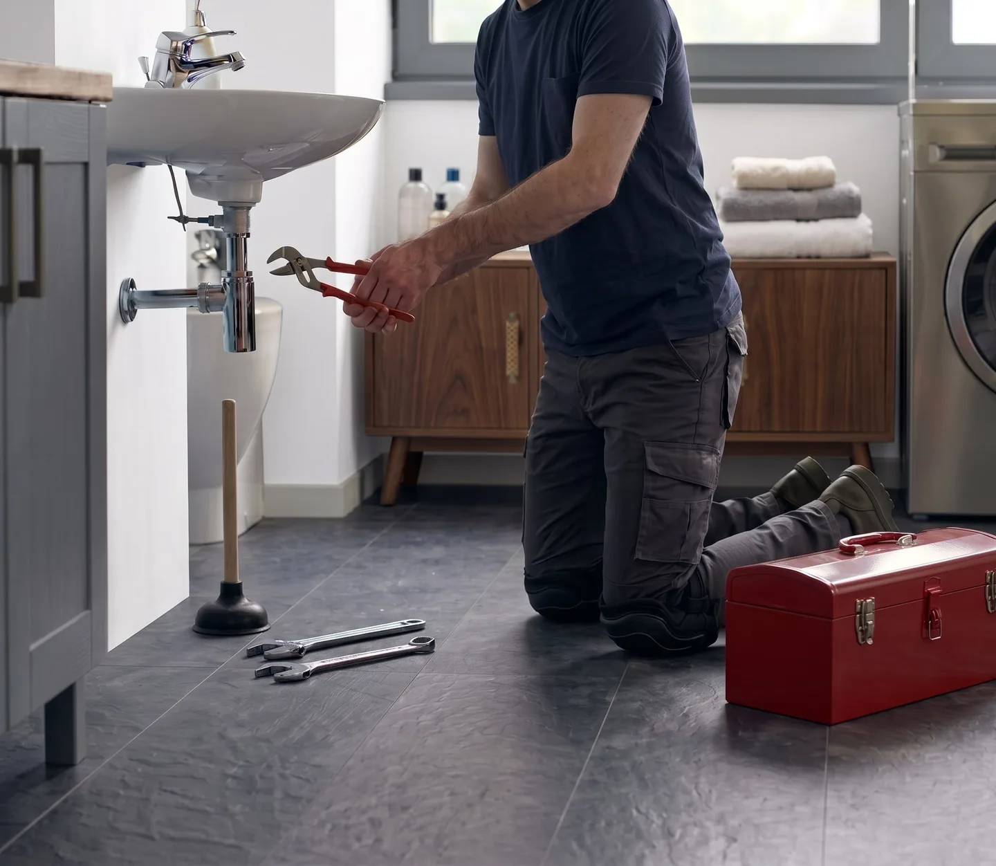 Installateur bei der Arbeit am Siphon eines Waschbeckens