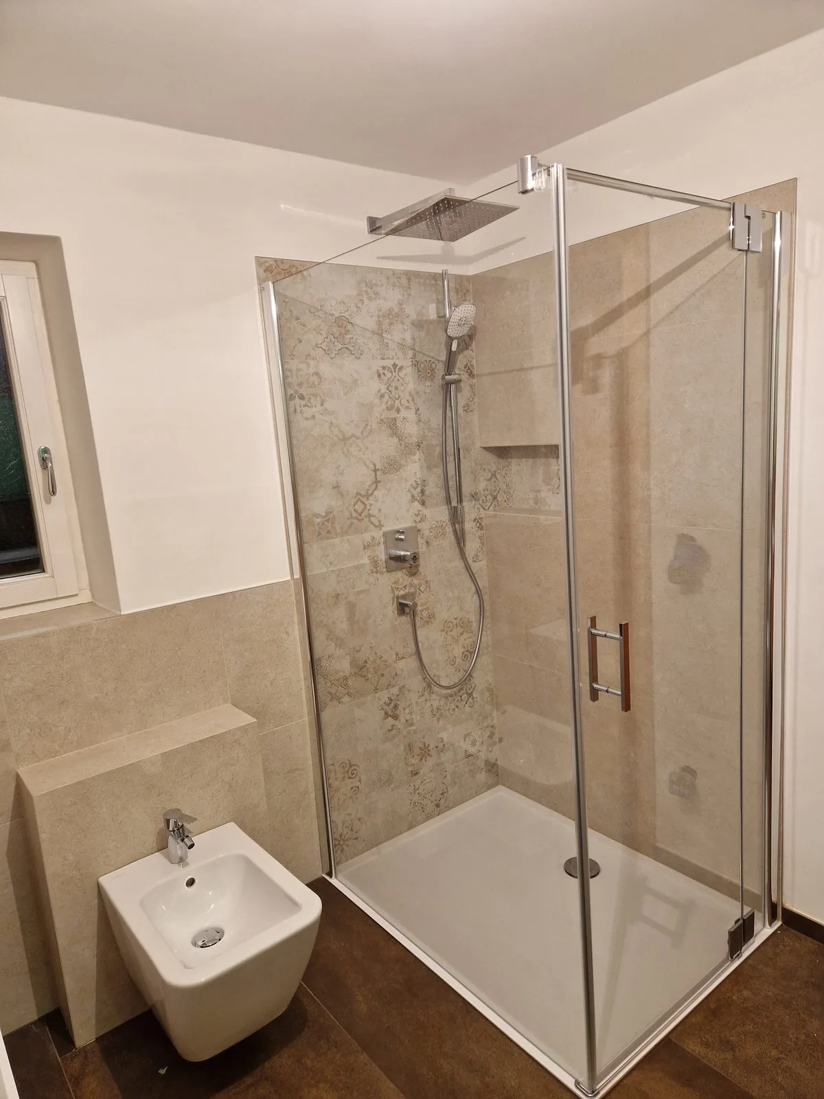 Glasdusche mit gemusterten Bodenfliesen und Bidet