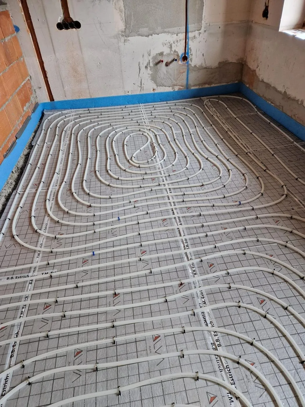 Fußbodenheizungsrohre in Schneckenform auf Dämmplatten verlegt