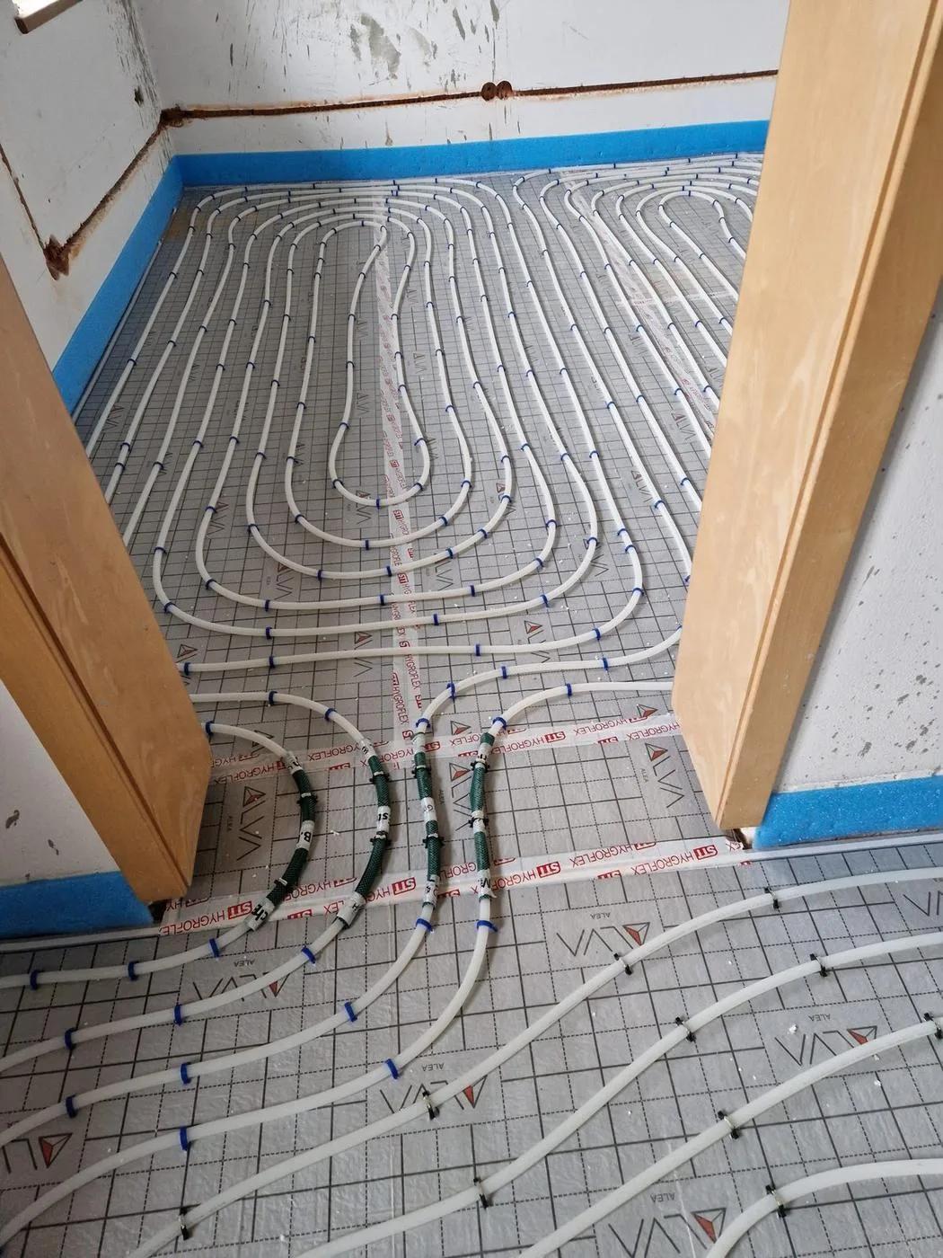 Fußbodenheizungsrohre auf Dämmplatten, verlegt um eine Holztreppe